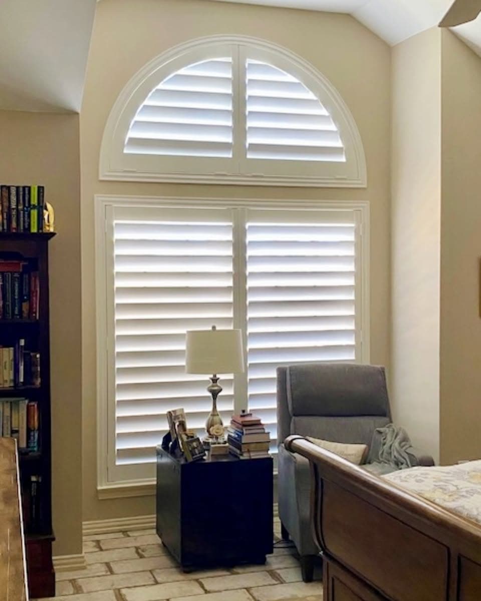 Tall arched specialty windows fitted with custom white shutters in a luxury two-story Sarasota great room by Sarasota Window Blinds