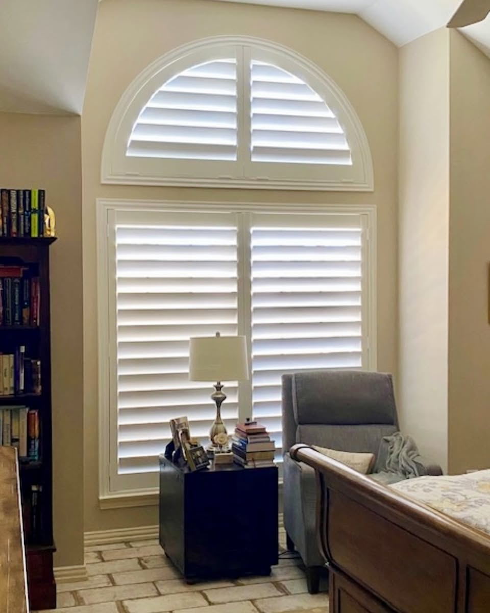 Tall arched specialty windows fitted with custom white shutters in a luxury two-story Sarasota great room by Sarasota Window Blinds